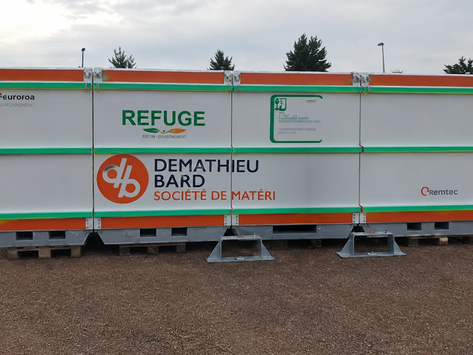 Conteneurs modulaires blancs à rayures orange et vertes, posés sur palettes métalliques avec pieds réglables en acier galvanisé