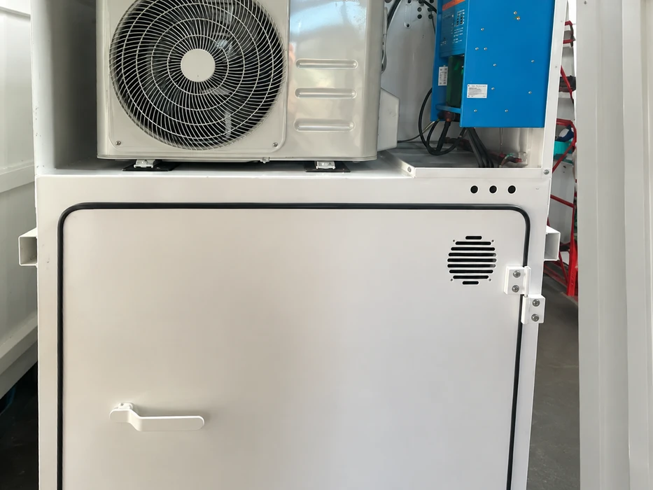 Installation technique en espace confiné : unité extérieure de climatisation split-system montée en hauteur, onduleur/chargeur bleu (type Victron ou similaire) avec câblage visible